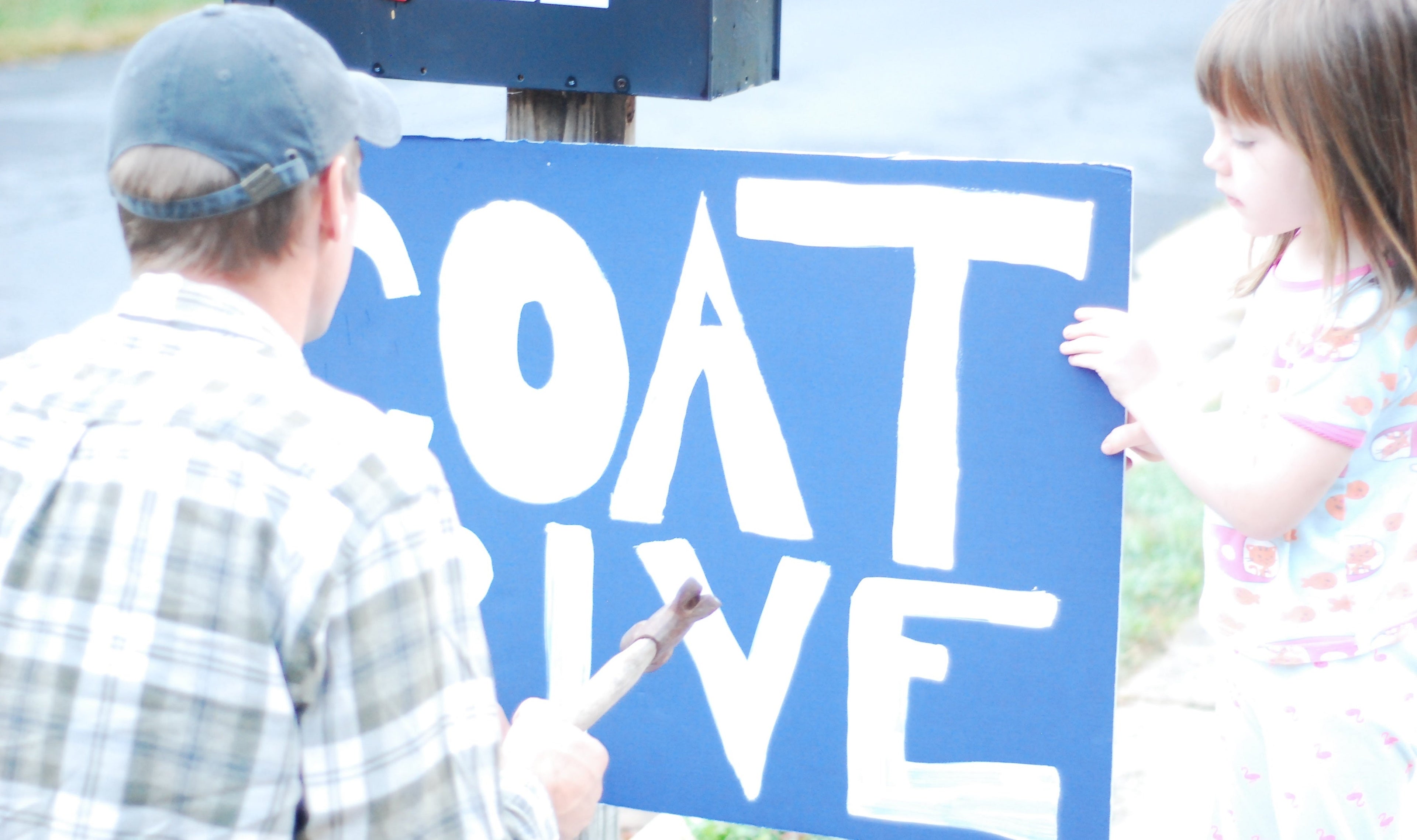 adult and kid painting a sign for a coat drive