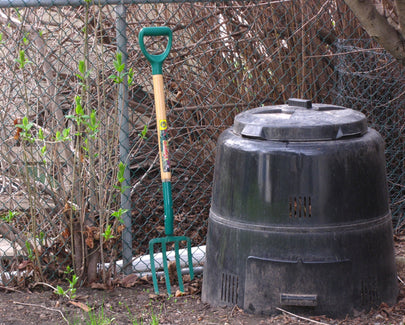 compost bin in yad next to fence with rake