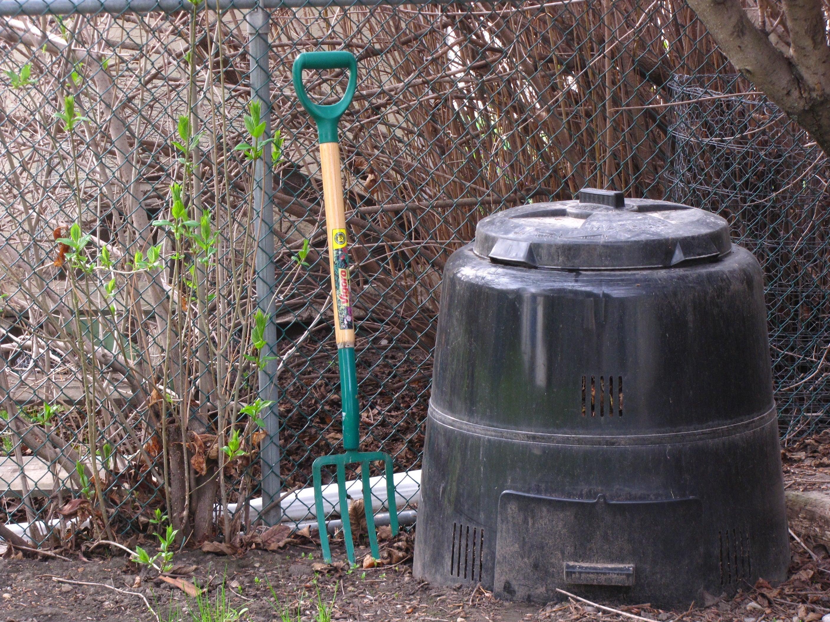 compost bin in yad next to fence with rake