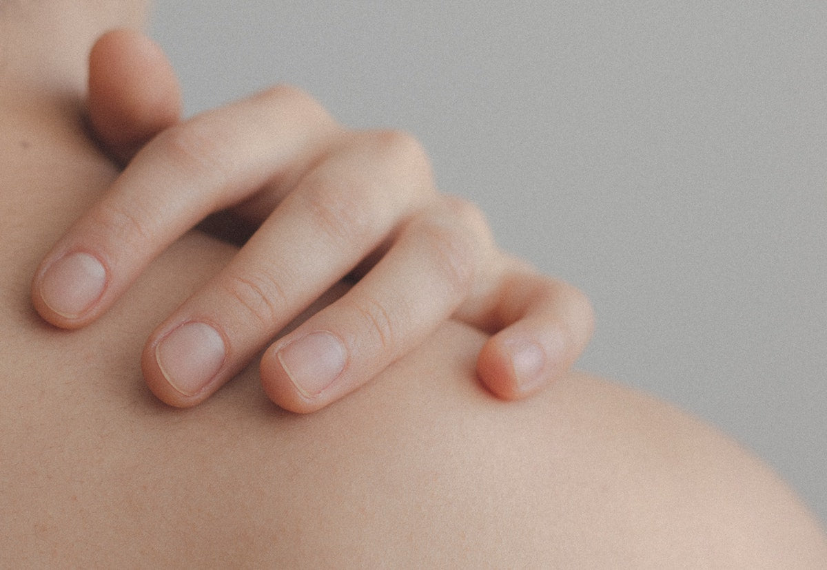 Women feeling skin on shoulder