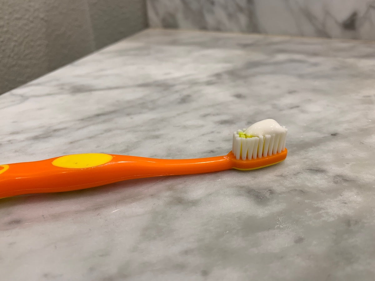 orange toothbrush with toothpaste