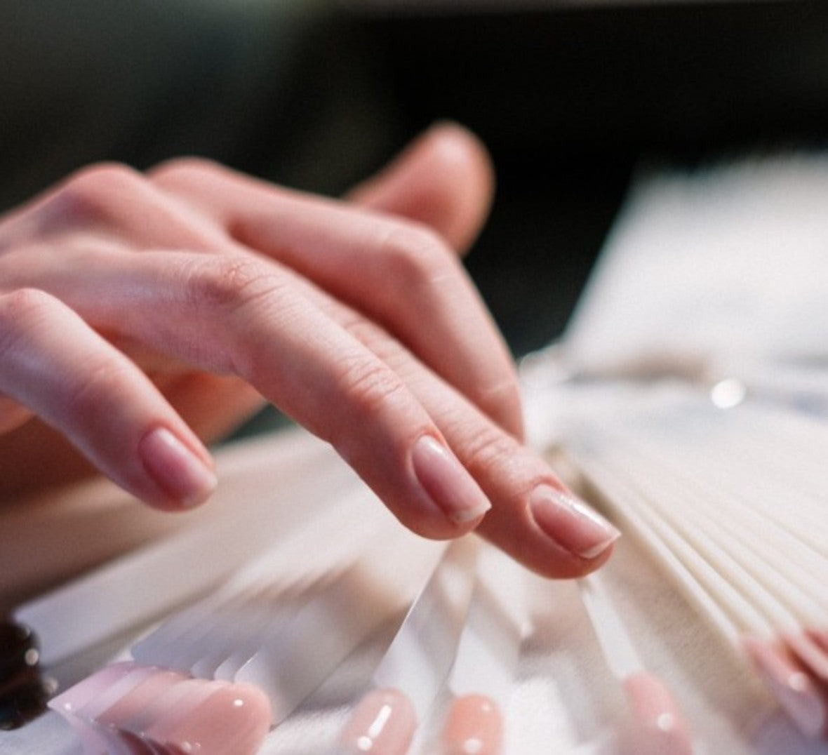 unpolished nails looking at a handful of gel polishes on a stick