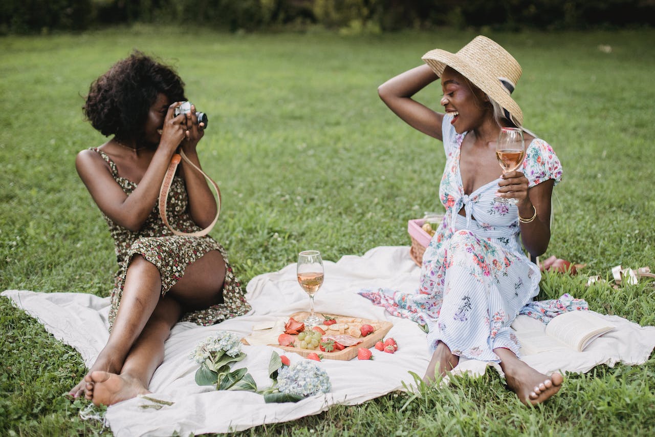 two women at a park eating, drinking and taking photos