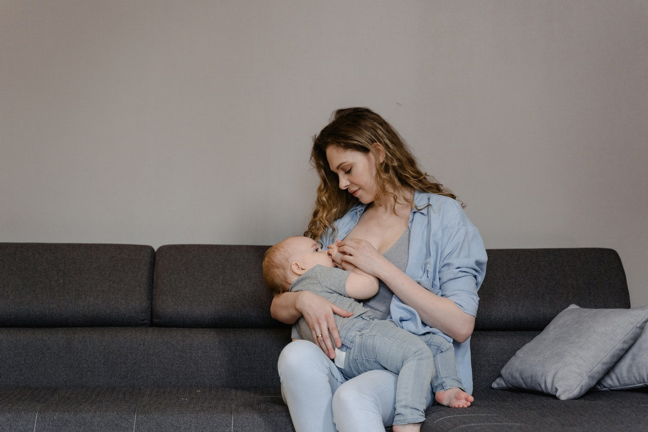 Woman Breastfeeding Her Baby while Sitting on the Couch