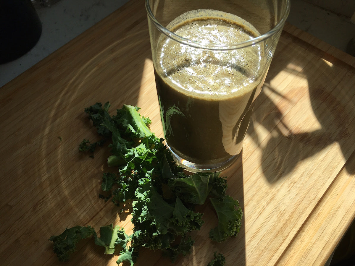 green juice in glass with kale next to glass