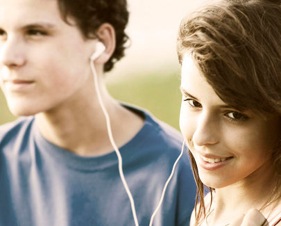 Teens sharing earphones, listening to music outdoor.