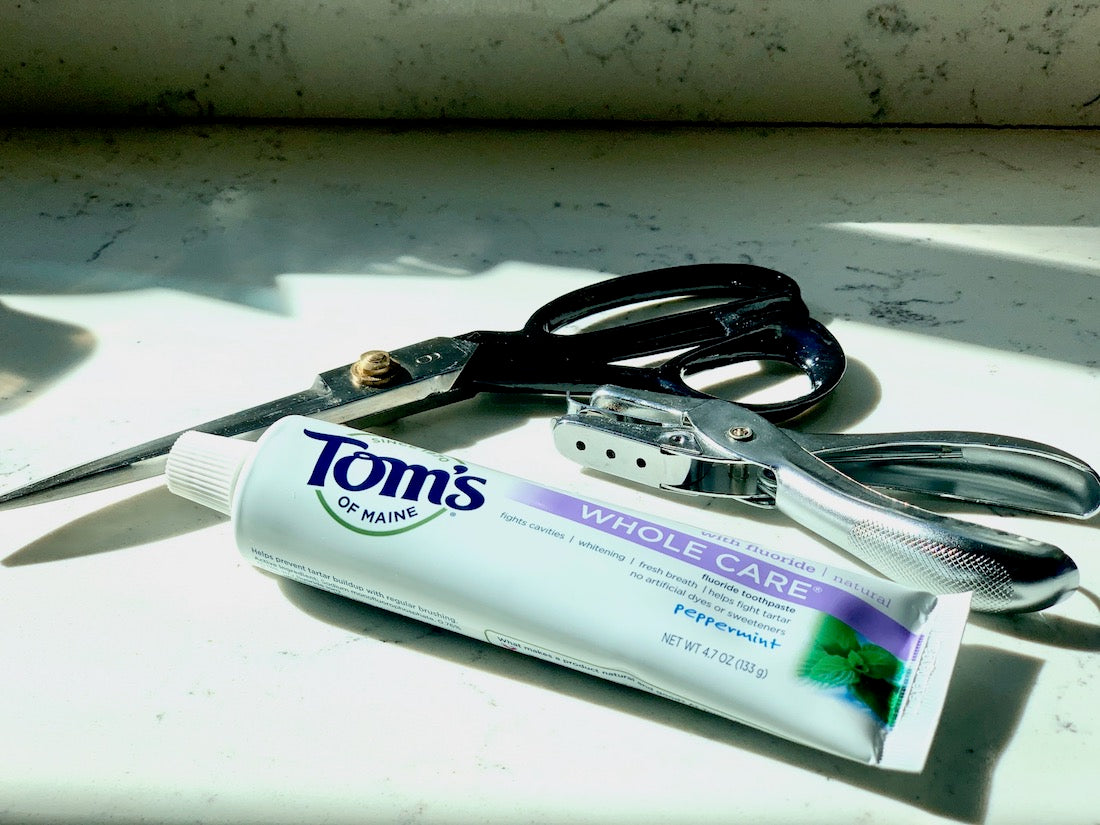 scissors, hole puncher and toms of Maine toothpaste tube