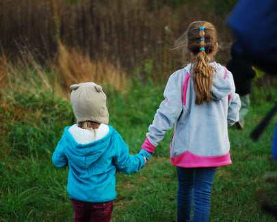 two young kids holding hands in a field