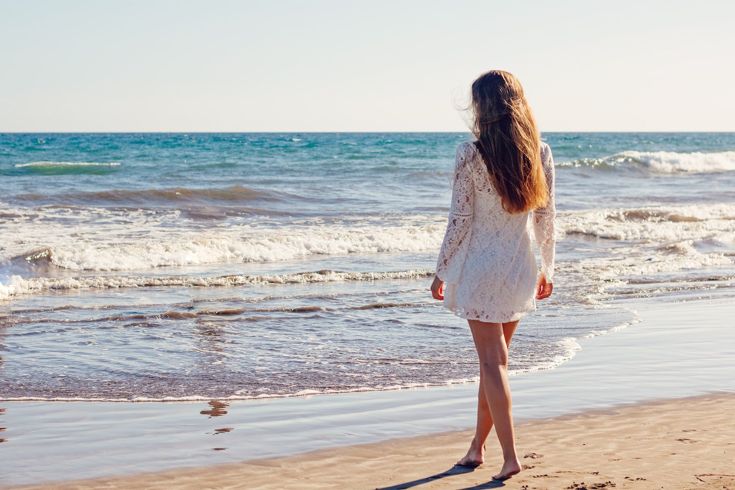 Woman on beach with ocean water in front of her