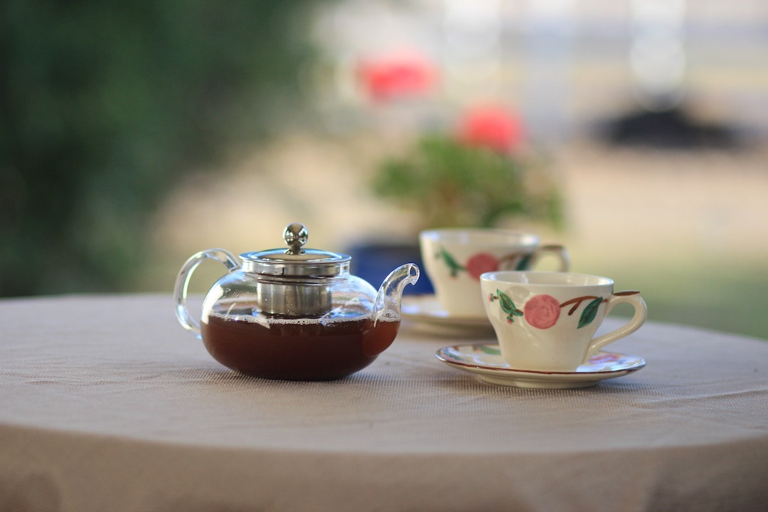 Clear Glass Teapot Near Teacups on Table