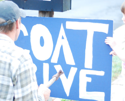 adult and kid painting a sign for a coat drive