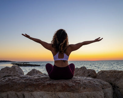 woman sitting on the stone in front of the ocean