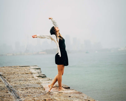 woman in black dress standing on concrete dock during daytime