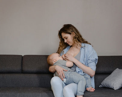  Woman Breastfeeding Her Baby while Sitting on the Couch
