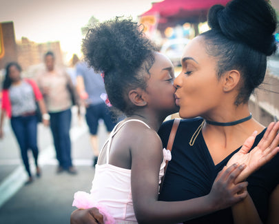 mom kissing daughter on cheek