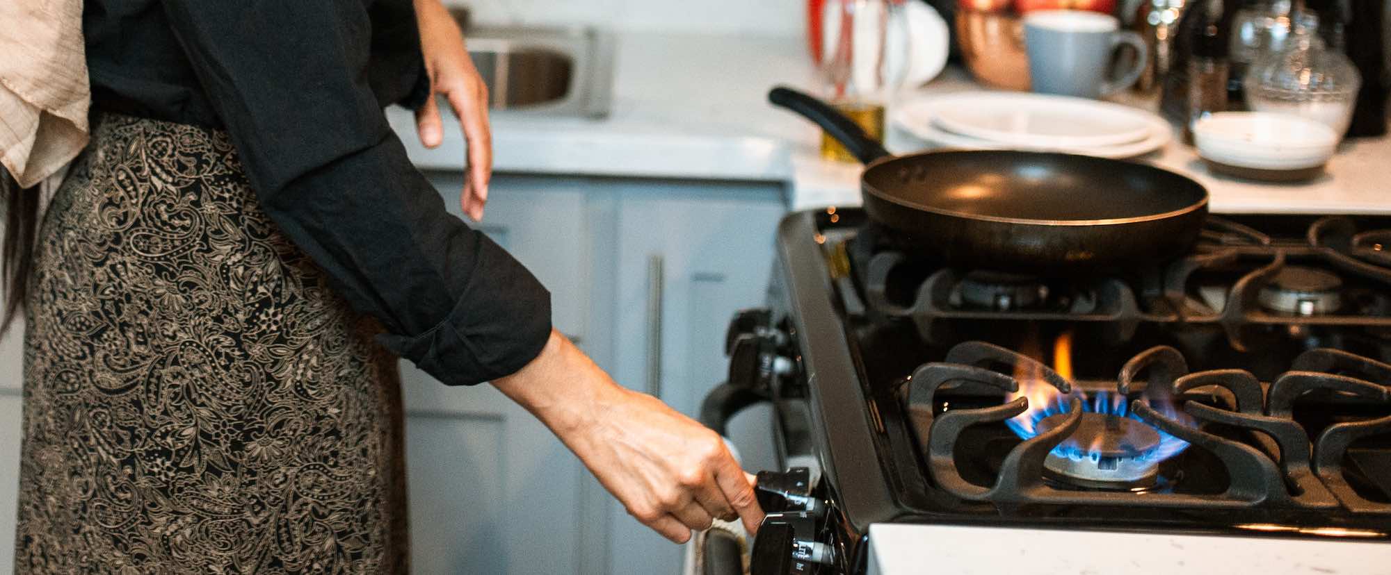 Ethnic woman in headscarf switching on stove