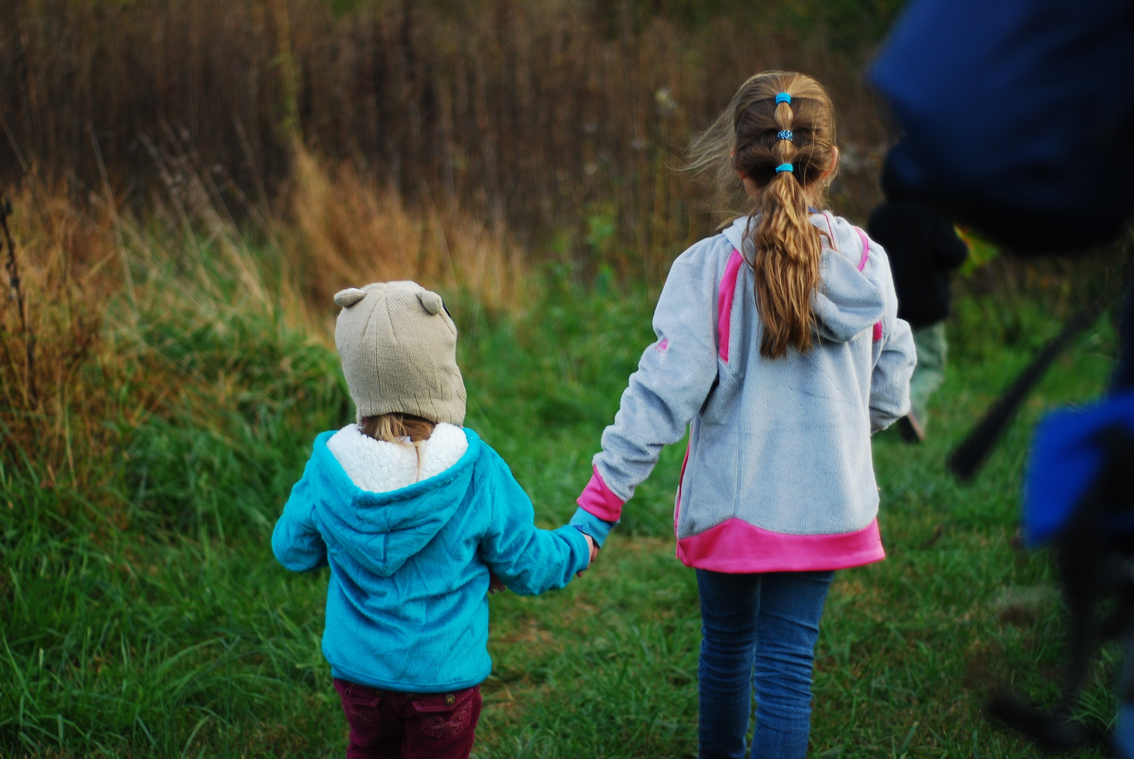 two young kids holding hands in a field