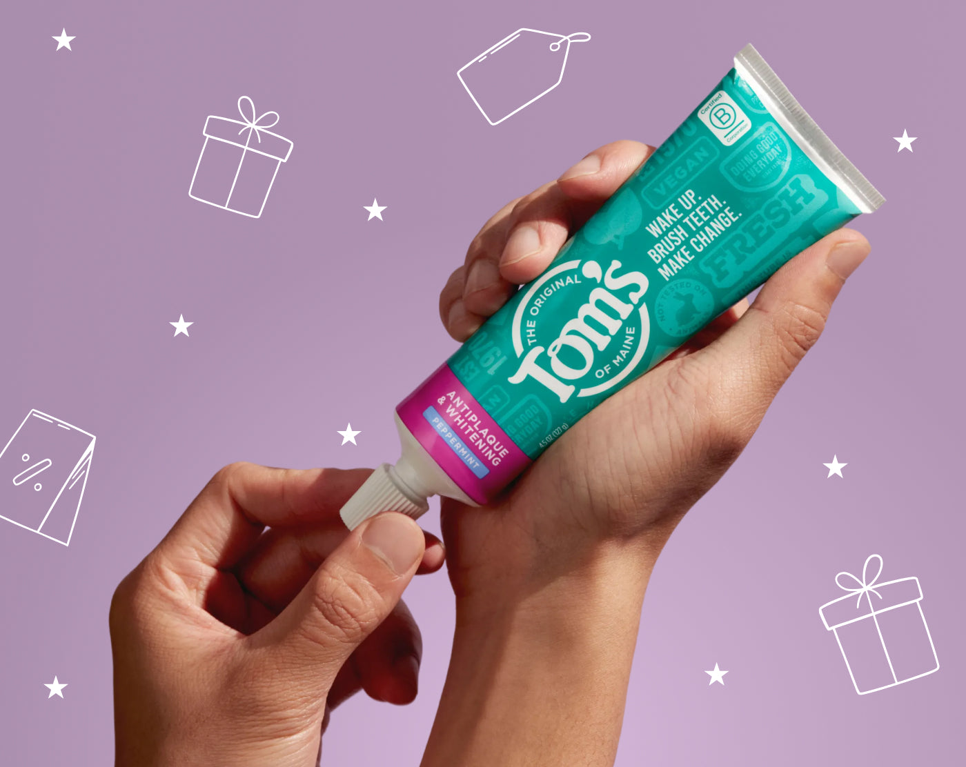 Hand holding a tube of Tom's of Maine makeup brush cleaner against a purple background with gift icons.