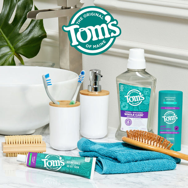 Whole care mouthwash, deodorant, and toothpaste set up on a bathroom sink